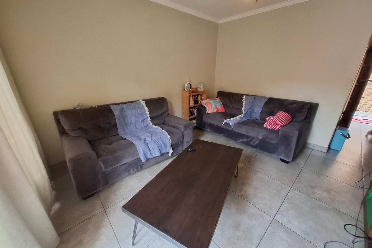 A living room area featuring neutral wall tones and tiled flooring, providing a functional and versatile space for relaxation.