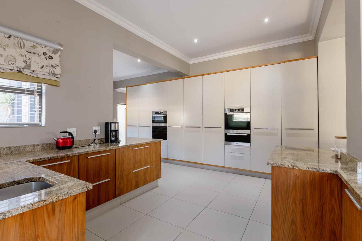 Modern kitchen featuring granite countertops, extensive built-in cabinetry, integrated appliances, and tiled flooring with recessed lighting.