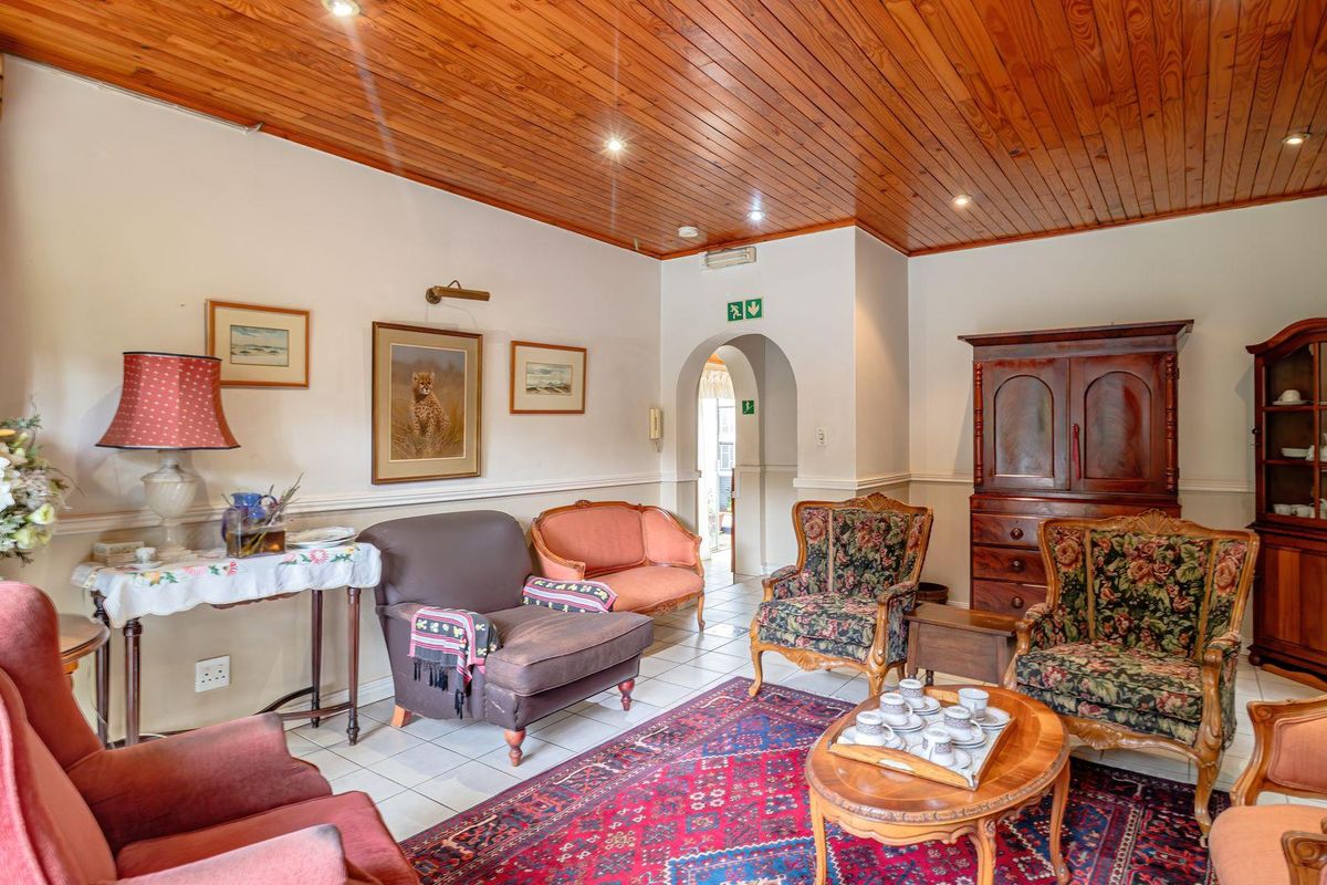 A traditional living room featuring a warm timber-paneled ceiling, tiled flooring, and an arched doorway leading to an adjoining space.