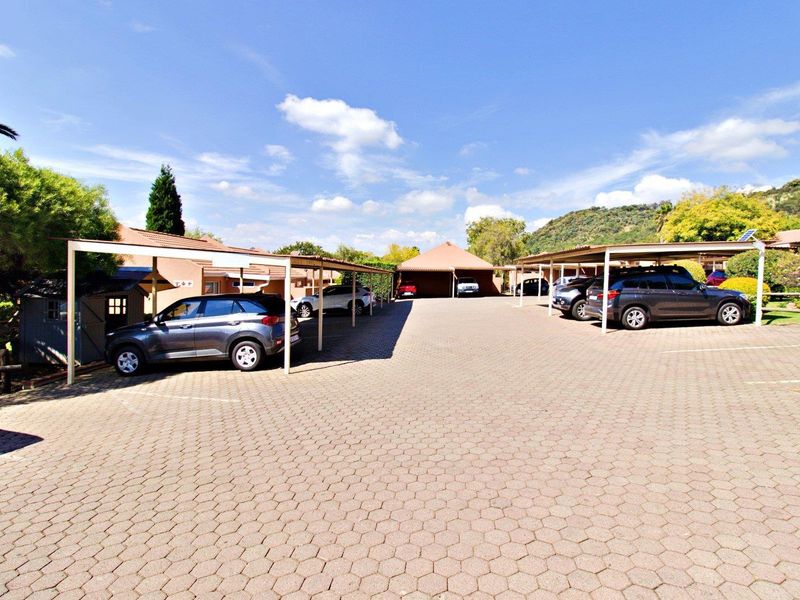 A spacious paved parking area featuring multiple covered carport bays within a well-maintained cluster complex setting.