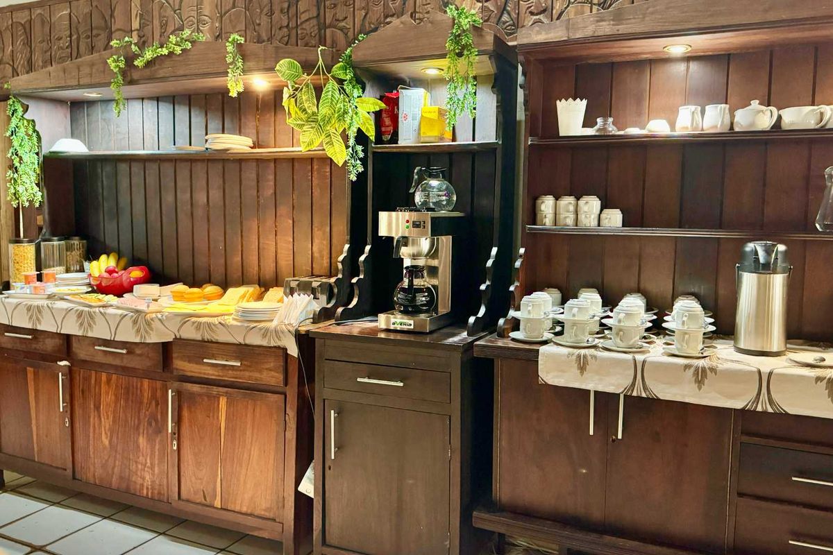 A rustic breakfast station featuring dark wood cabinetry, integrated shelving, and tiled flooring, designed for efficient food and beverage service in a lodge setting.