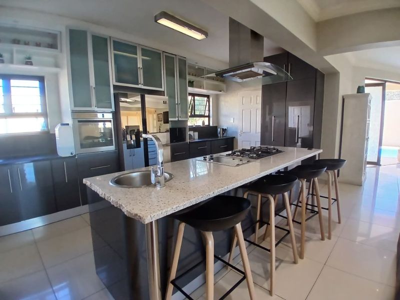 Modern kitchen featuring a central island with a built-in gas hob, stone countertops, sleek cabinetry, and a stainless steel extractor fan.