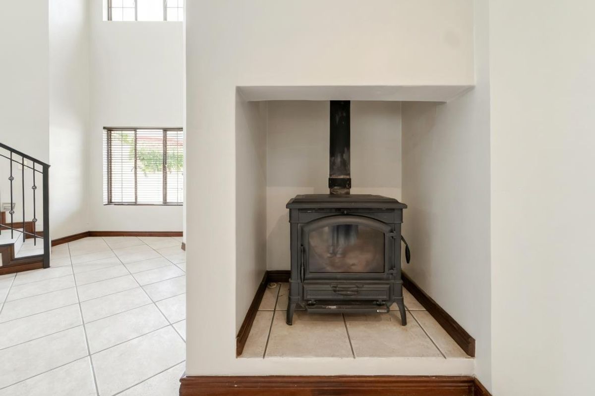 A bright living area featuring a built-in cast iron fireplace, tiled flooring, and a staircase with a decorative metal railing.