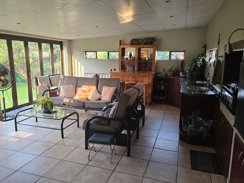 Spacious open-plan living area featuring tiled floors, a built-in bar with sink, and large bi-fold doors providing seamless access to the garden.