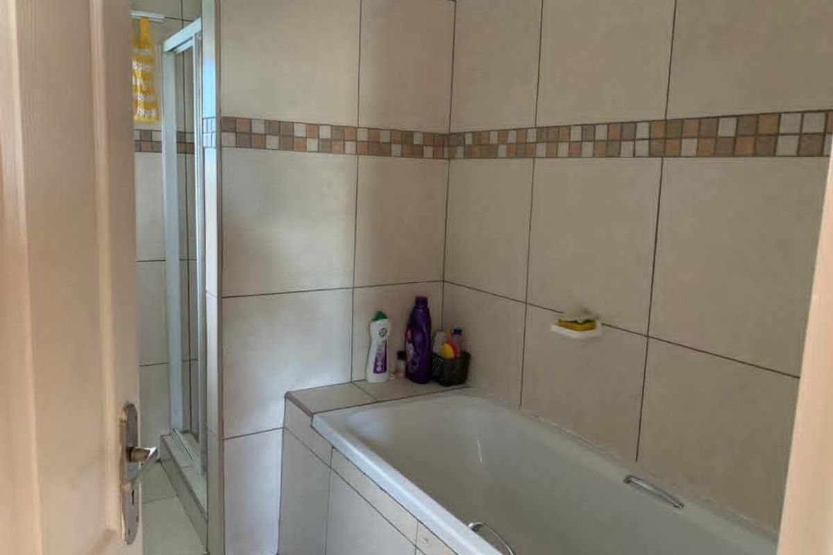 A functional bathroom featuring a built-in bathtub, a separate shower enclosure, and neutral ceramic wall and floor tiling.