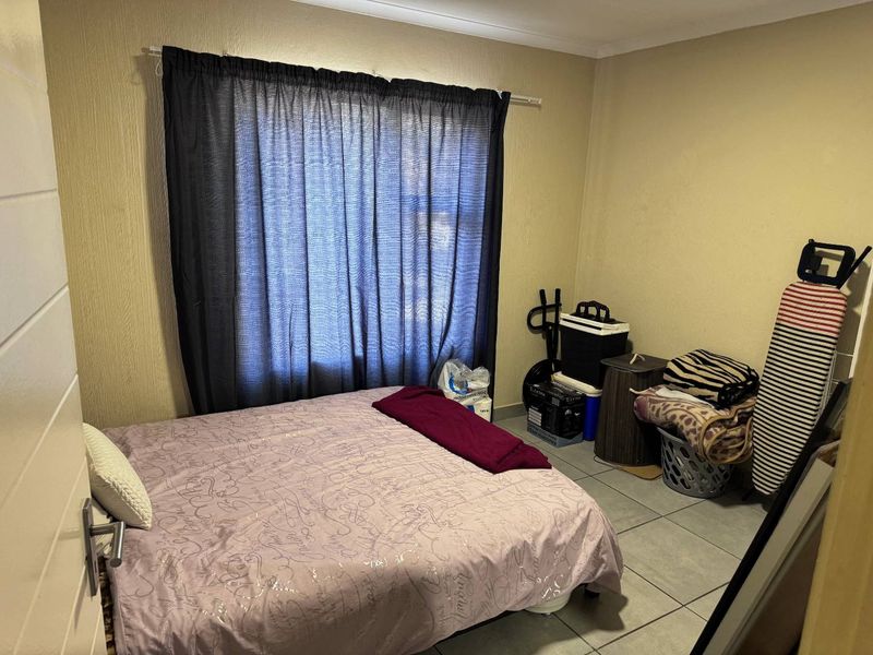 A standard bedroom featuring tiled flooring and a window with a curtain rail, providing a functional space for rest.