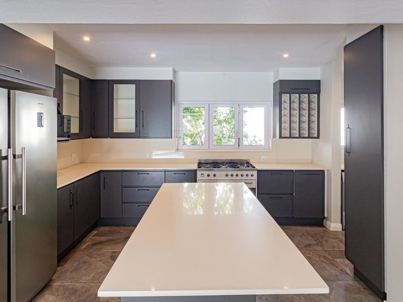 Modern kitchen featuring dark cabinetry, a central island with quartz countertops, gas stove, and tiled flooring with recessed lighting.