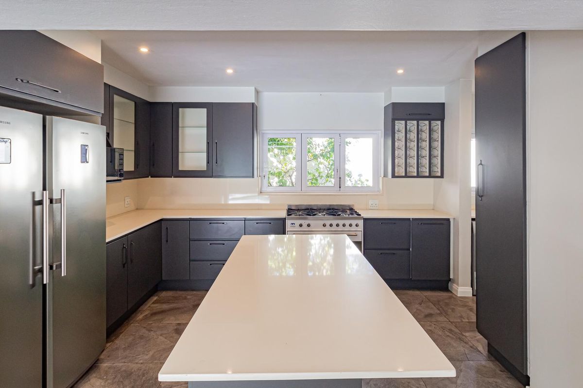 Modern kitchen featuring dark cabinetry, a central island with quartz countertops, gas stove, and tiled flooring with recessed lighting.