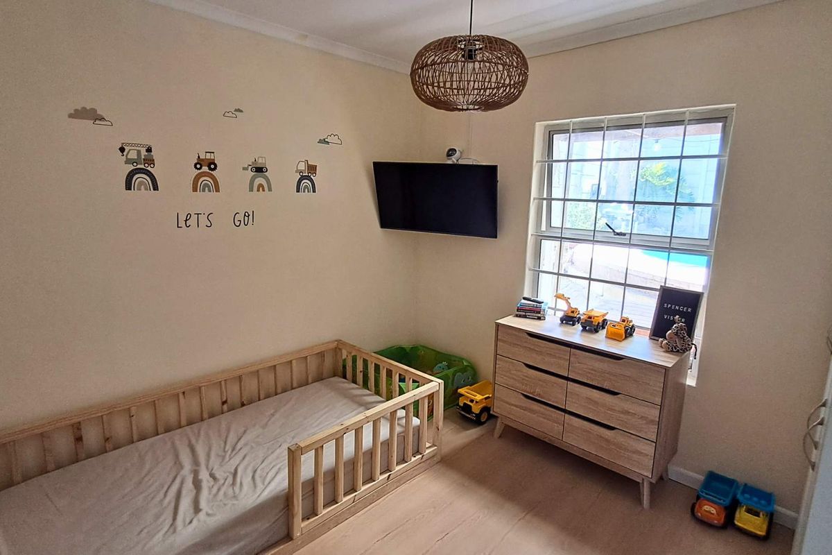 A functional bedroom featuring a window with security bars and a wall-mounted television.