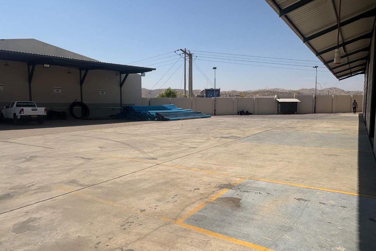 Expansive industrial yard featuring a large concrete loading area, covered canopy sections, and perimeter walling, suitable for logistics or storage operations.
