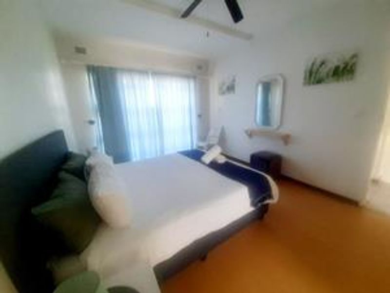 A bedroom featuring a ceiling fan and sliding glass doors that provide natural light.