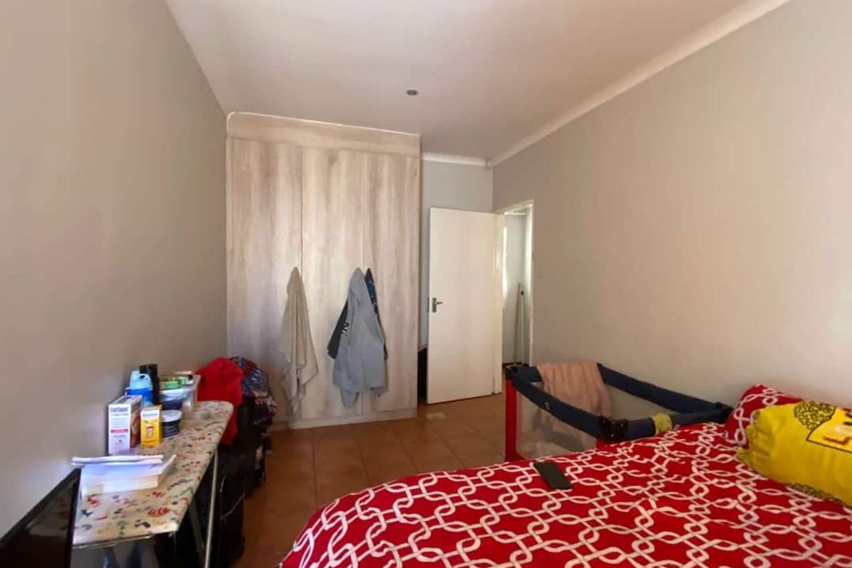 A bedroom featuring built-in wooden cupboards and tiled flooring, providing functional storage space.