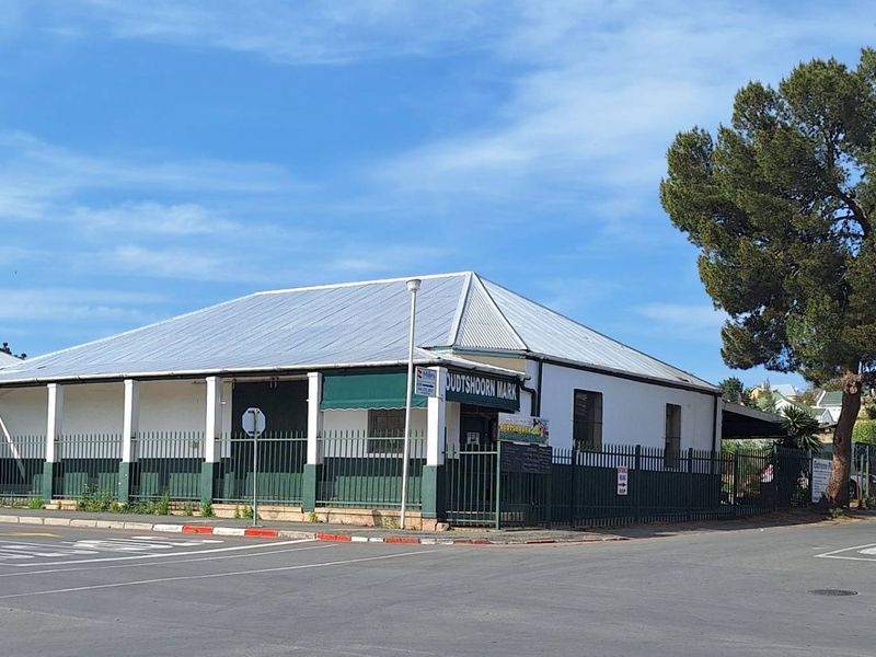 Street-facing view of an industrial property featuring a corrugated metal roof, perimeter steel fencing, and a covered veranda area.