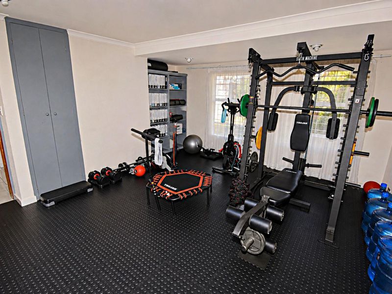 A dedicated home gym space featuring durable rubber flooring, built-in storage cupboards, and coving detail.