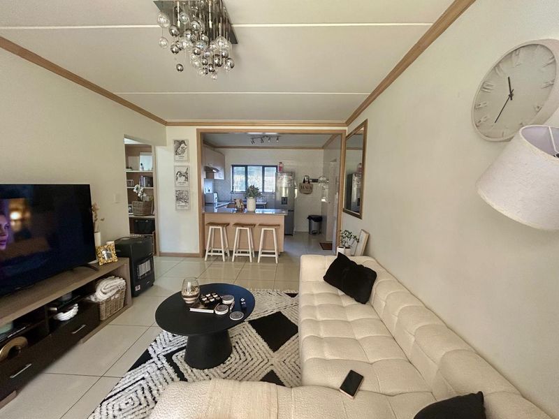 Open-plan living area featuring tiled floors, a central kitchen island with breakfast bar seating, and a modern chandelier, creating a cohesive living space.