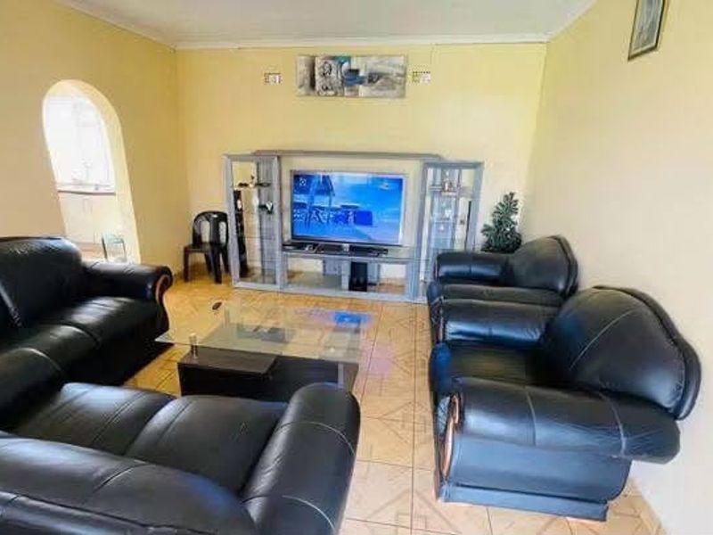 A living room featuring tiled flooring, an arched entryway, and a built-in entertainment unit.
