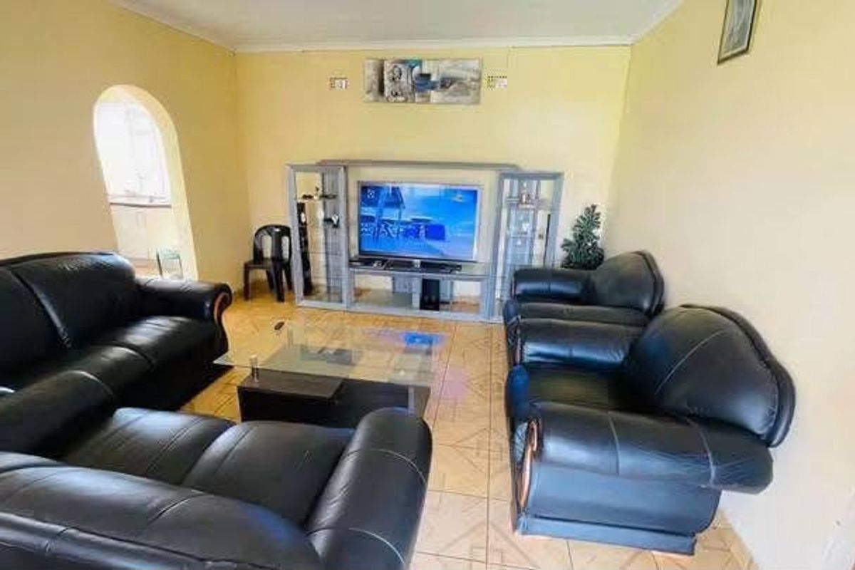 A living room featuring tiled flooring, an arched entryway, and a built-in entertainment unit.