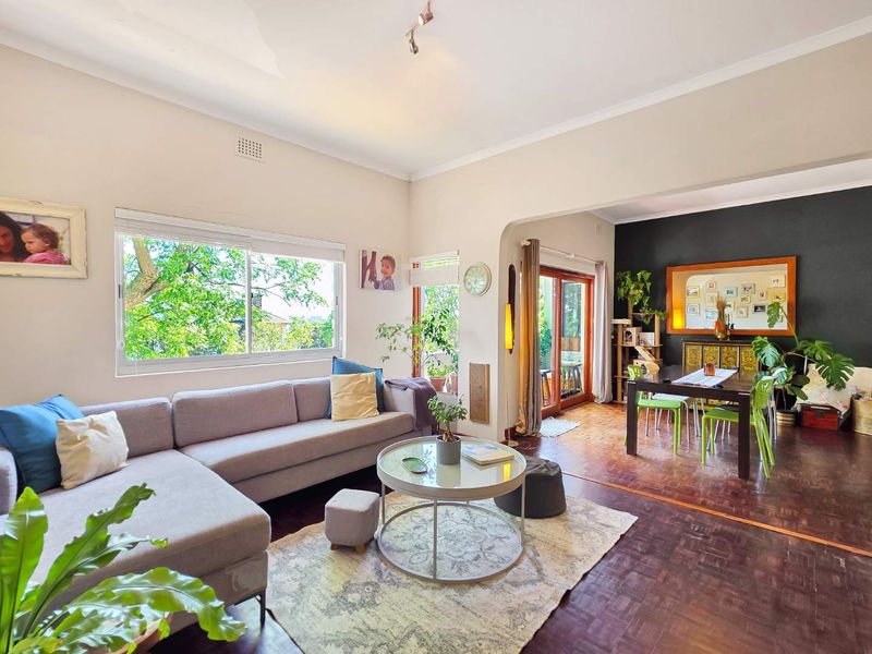 Spacious open-plan living and dining area featuring classic parquet flooring, an elegant archway, and large windows that provide ample natural light.