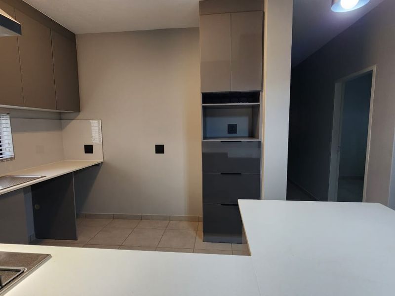 Modern kitchen featuring sleek grey cabinetry, stone countertops, a gas hob, and integrated extractor fan, offering a clean and functional culinary space.
