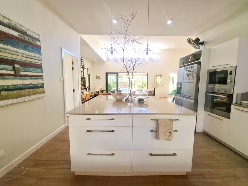 Modern open-plan kitchen featuring a central island with stone countertops, integrated appliances, and sleek cabinetry, flowing into the living area.