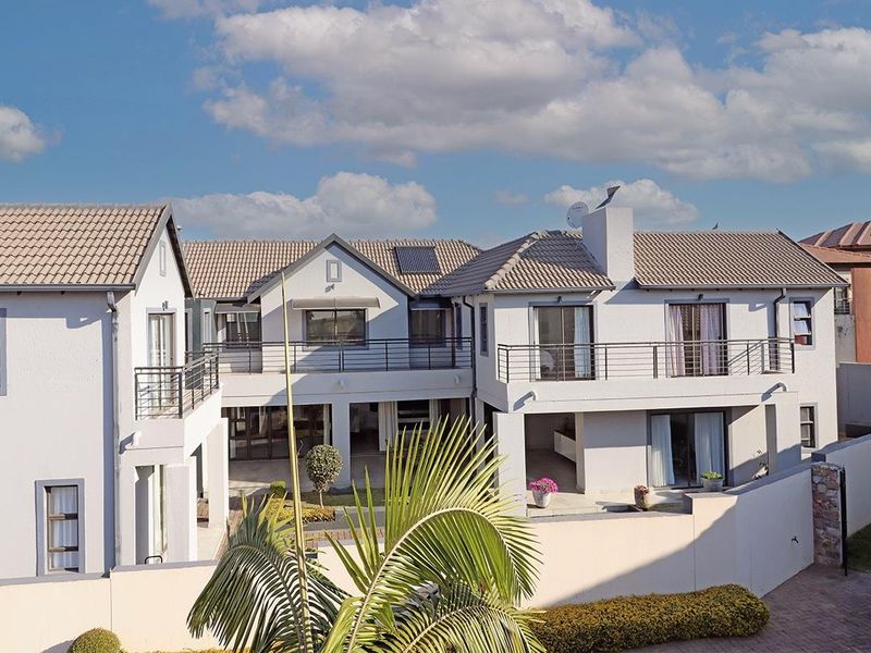 Rear view of a multi-story residential property featuring tiled roofing, upper-level balconies with metal railings, and a private courtyard area.