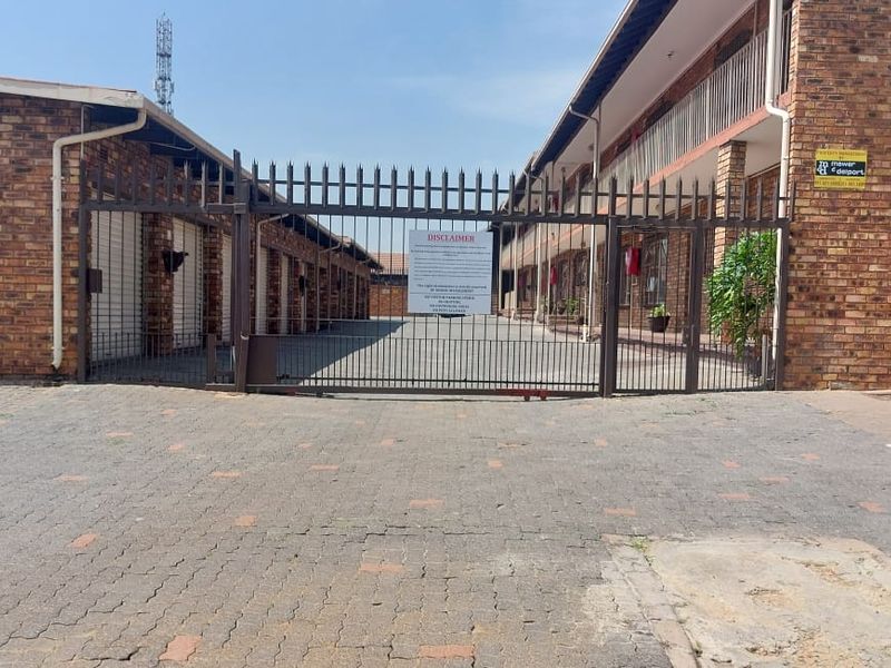 Exterior view of the apartment complex entrance featuring a secure gated driveway, brick facade, and paved access area.