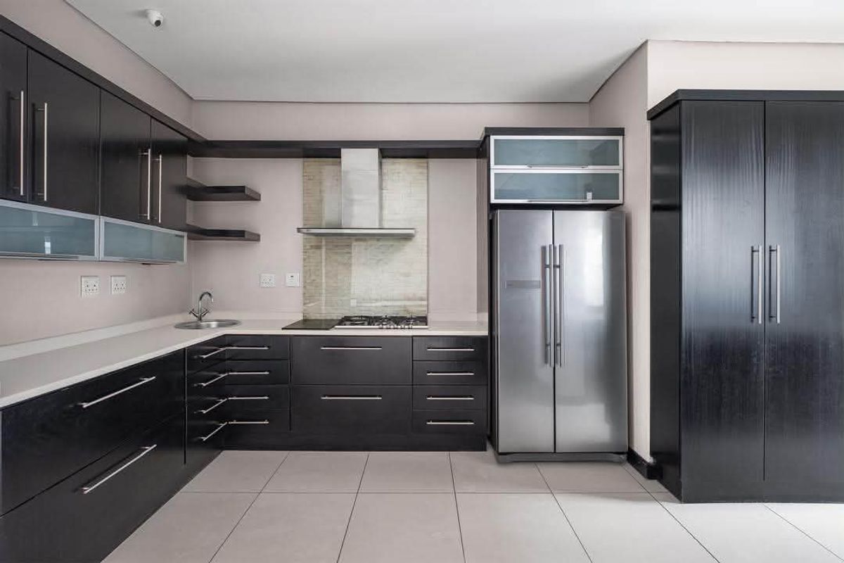 Modern kitchen featuring dark wood cabinetry, stone countertops, stainless steel appliances, and tiled flooring in a clean, contemporary layout.