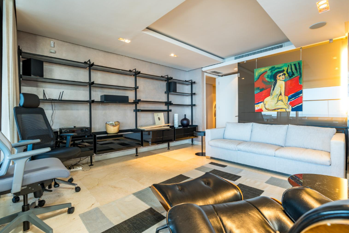 A modern living room featuring stone flooring, recessed ceiling lighting, ducted air conditioning, and a large built-in shelving unit.