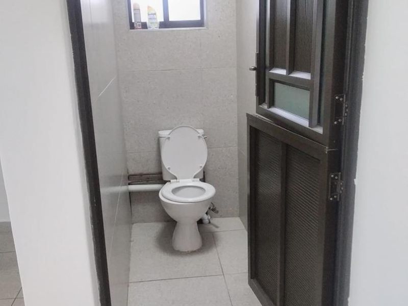 A compact, functional bathroom featuring tiled walls and flooring, a standard toilet, and an aluminium door.