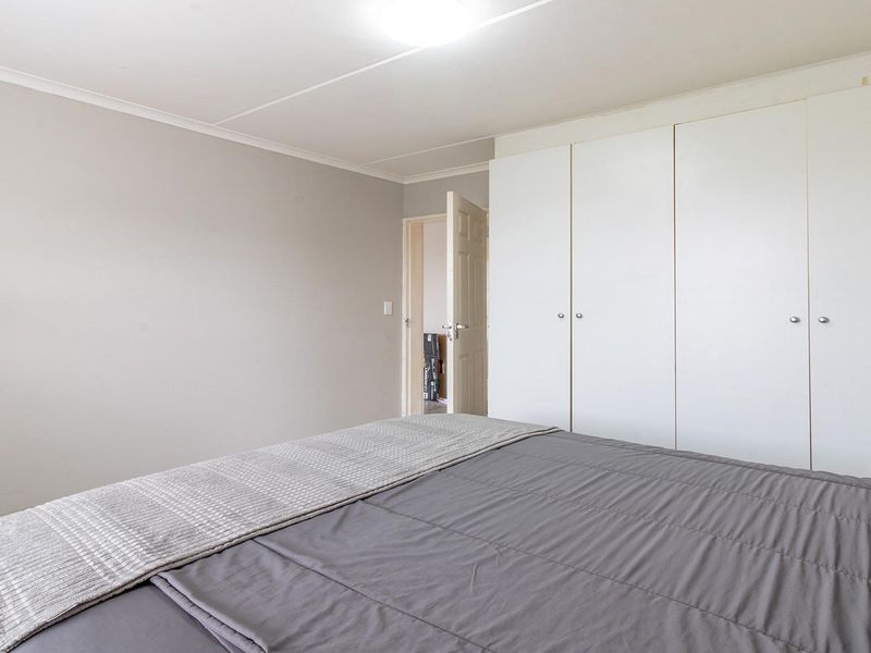A functional bedroom featuring neutral walls and ample built-in cupboard storage space.