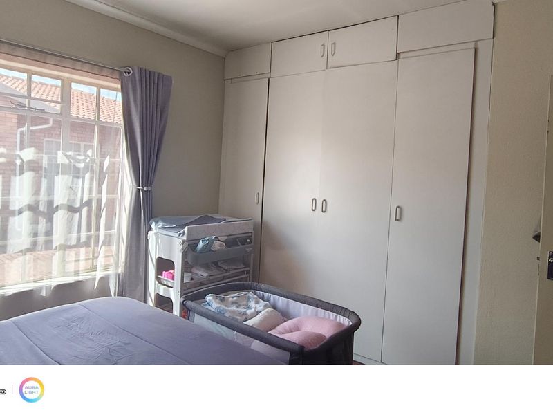 A bedroom featuring built-in cupboards and a large window providing natural light.