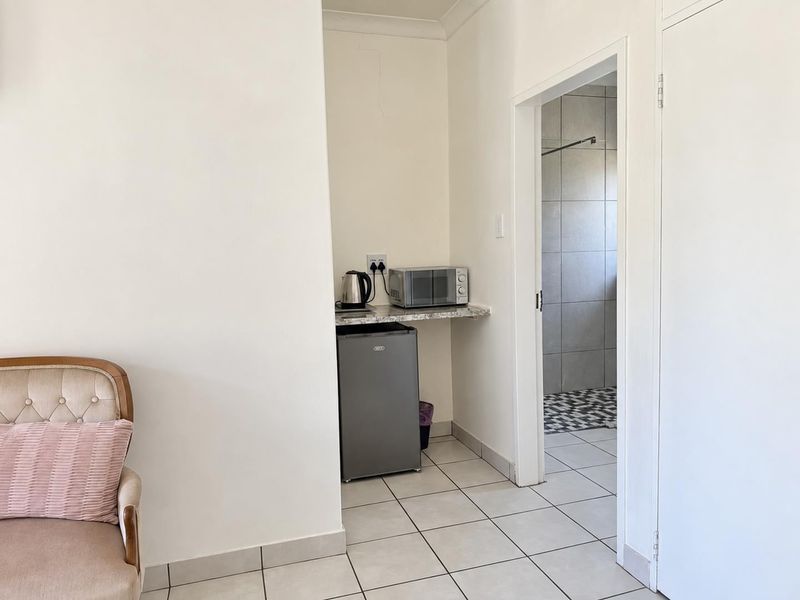 A compact utility nook featuring a granite countertop and tiled flooring, providing convenient access to the adjacent bathroom.