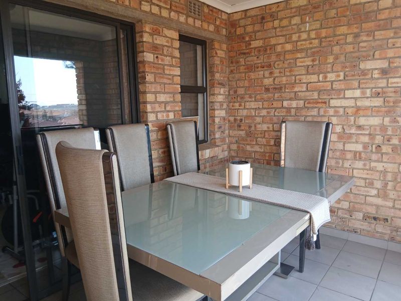 A covered patio area featuring exposed brick walls, tiled flooring, and large sliding glass doors providing access to the interior living space.