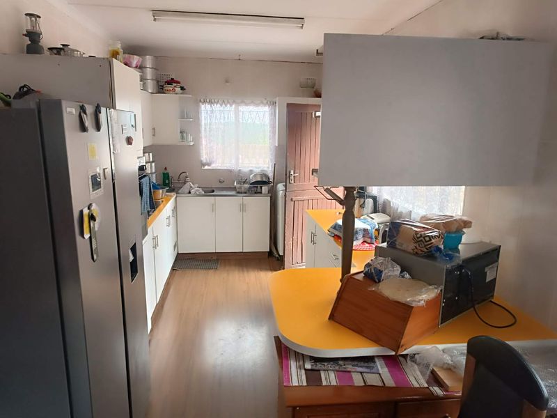 A functional kitchen featuring white cabinetry, laminate countertops, and a stainless steel sink, offering a practical layout with potential for modern updates.