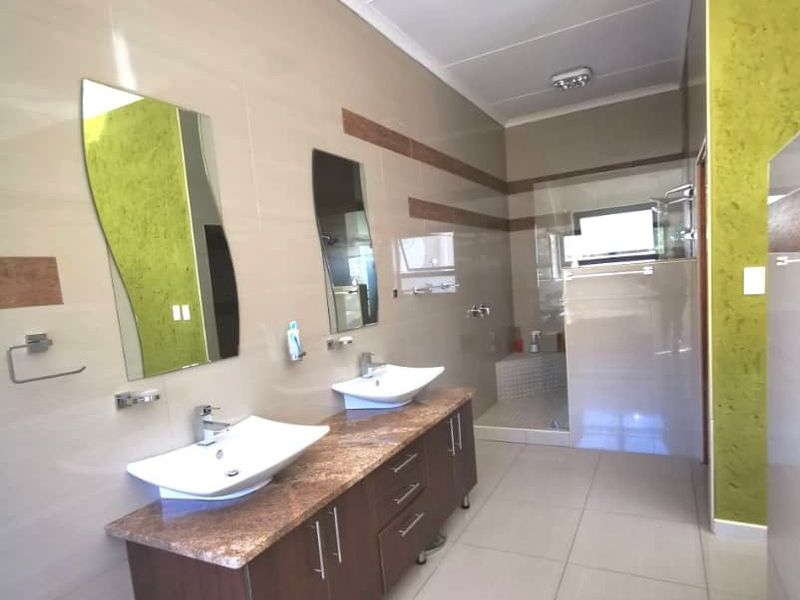 Modern bathroom featuring a double vanity with vessel sinks, granite countertop, and a spacious walk-in shower with a glass enclosure.