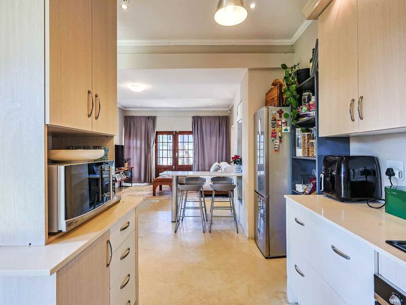 Open-plan kitchen and living area featuring light wood cabinetry, laminate countertops, a breakfast bar, and direct access to the living space.