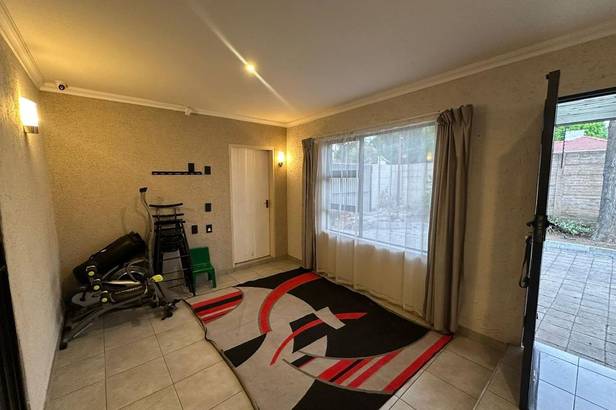 A functional living space featuring tiled flooring, large windows providing natural light, and direct access to an outdoor patio area.