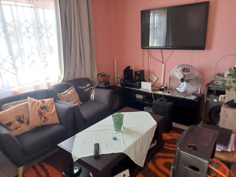 A living room area featuring a window with a security gate and curtain tracks, finished with painted walls.