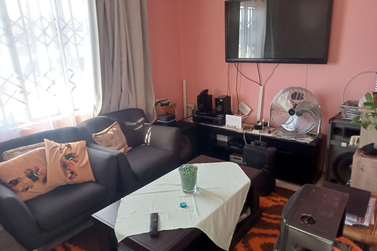 A living room area featuring a window with a security gate and curtain tracks, finished with painted walls.