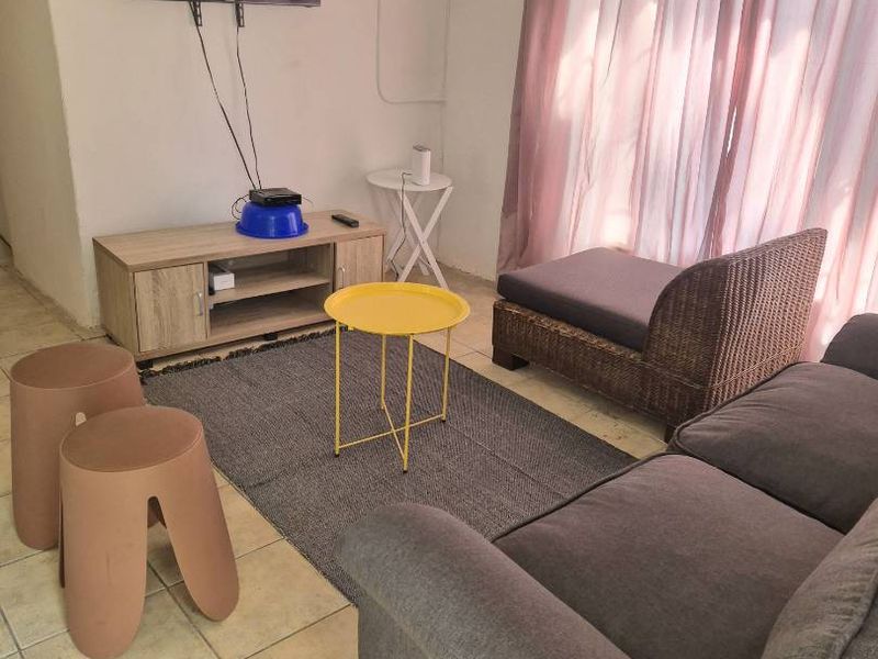 A living room area featuring tiled flooring and a wall-mounted electrical distribution board.