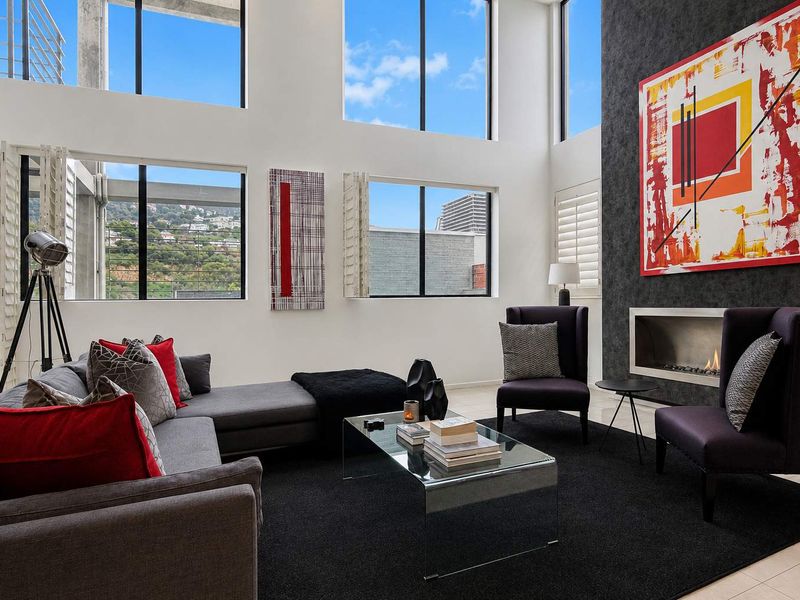Spacious double-volume living room featuring large windows, a modern built-in fireplace, and a striking black feature wall with high-quality finishes.