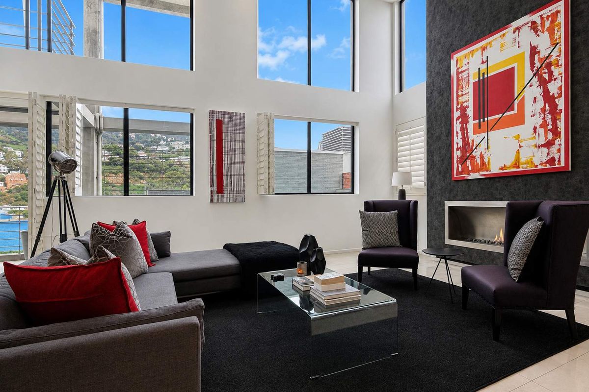 Spacious double-volume living room featuring large windows, a modern built-in fireplace, and a striking black feature wall with high-quality finishes.