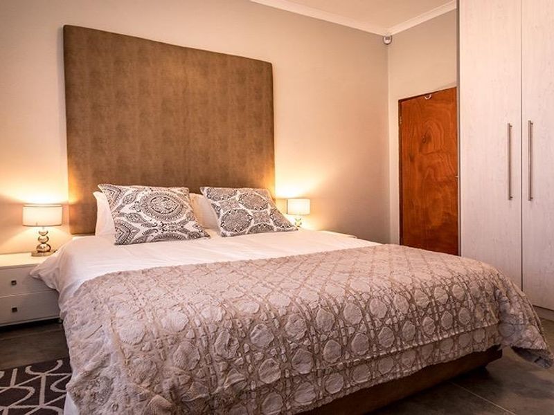 A well-maintained bedroom featuring neutral tones, tiled flooring, and ample built-in wardrobe storage.