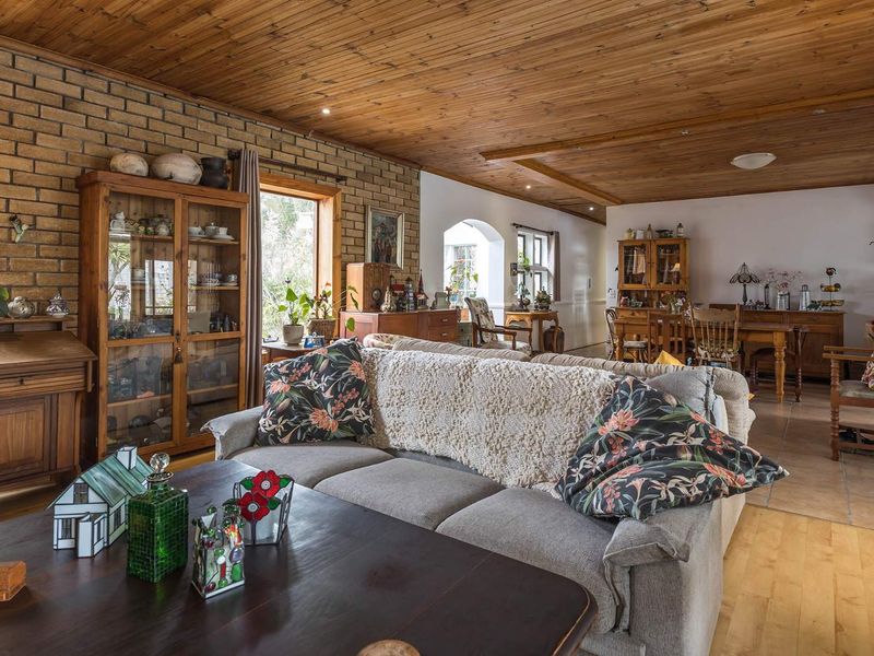 Spacious open-plan living and dining area featuring a warm timber ceiling, exposed brick feature wall, and a mix of tiled and timber flooring.