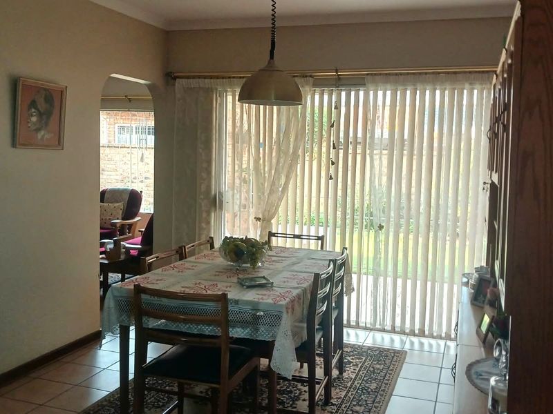 Dining room featuring tiled flooring, a pendant light fixture, and a sliding glass door with vertical blinds leading to the exterior.