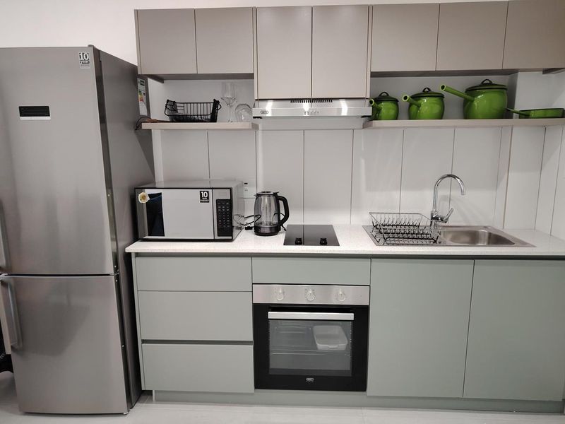 Modern kitchen featuring sleek cabinetry, stone countertops, integrated oven, electric hob, and stainless steel sink with contemporary finishes.
