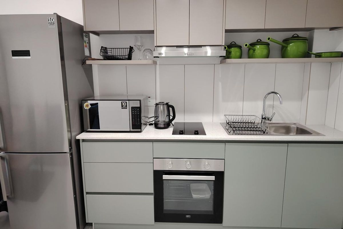 Modern kitchen featuring sleek cabinetry, stone countertops, integrated oven, electric hob, and stainless steel sink with contemporary finishes.
