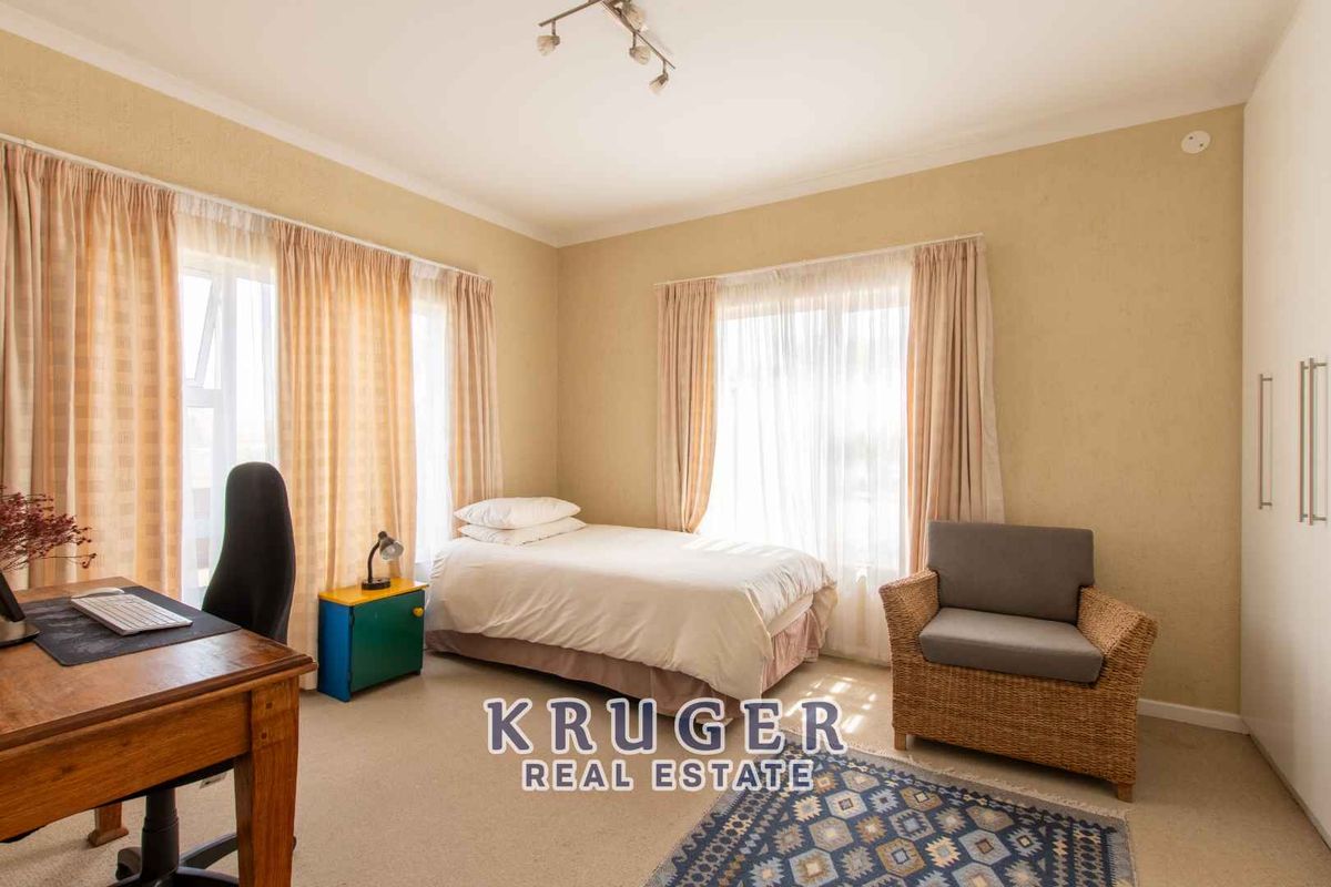 A well-lit bedroom featuring neutral walls, carpeted flooring, and built-in cupboards, offering a comfortable and functional living space.