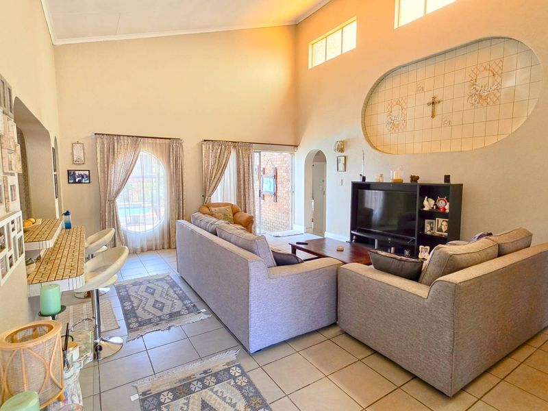 Spacious living room featuring high vaulted ceilings, tiled flooring, a unique decorative wall niche, and sliding glass doors leading to the outdoor area.