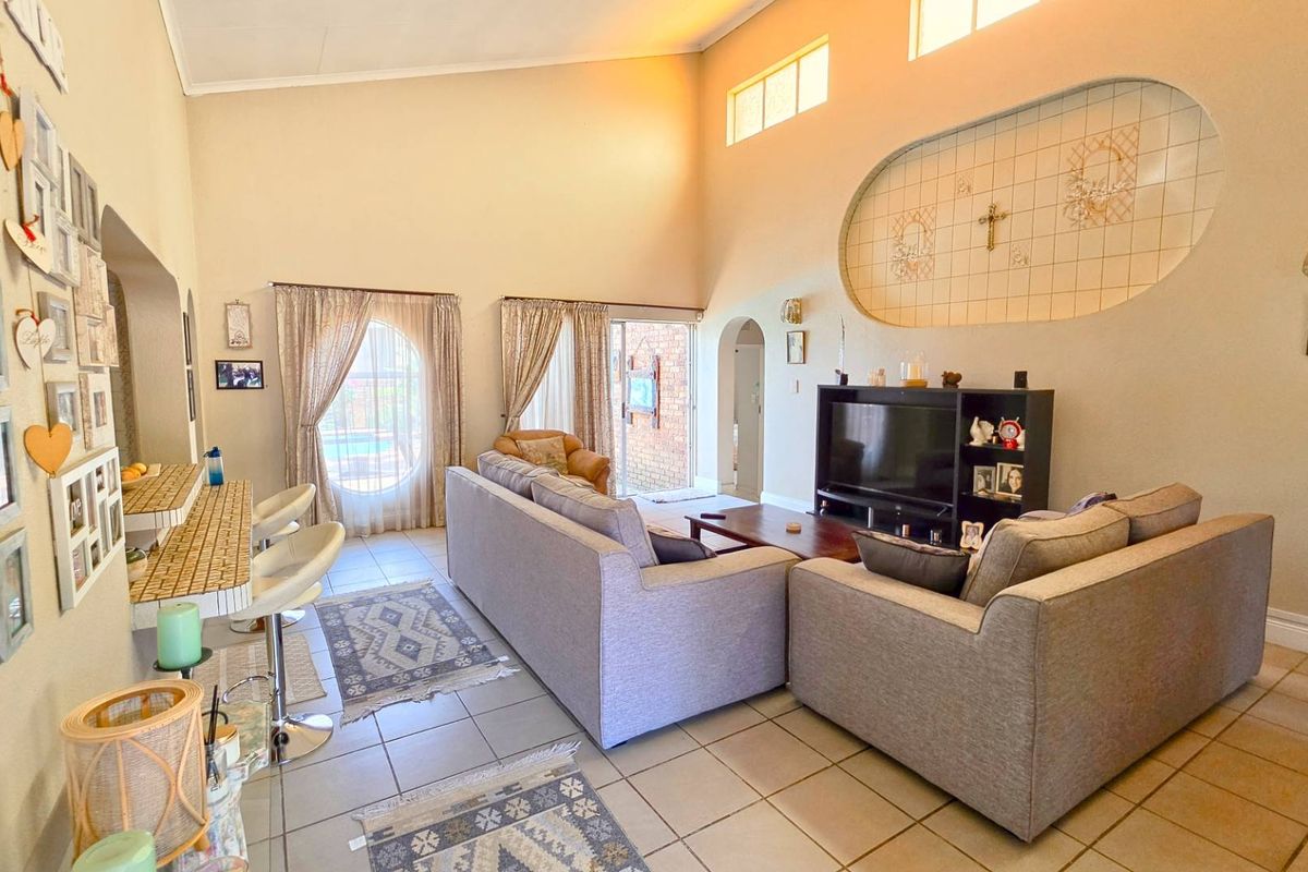 Spacious living room featuring high vaulted ceilings, tiled flooring, a unique decorative wall niche, and sliding glass doors leading to the outdoor area.